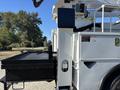 A 2013 International 7500 with a flatbed and an extended boom arm ready for operation