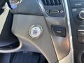 A close-up of the dashboard of a 2015 Hyundai Sonata featuring the engine start stop button and an econ mode button