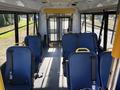 Interior view of a 2017 Ford Transit-350 with blue seats and yellow handles arranged in rows facing forward