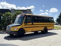 A yellow 2011 Freightliner B2 school bus is parked with multiple windows and black stripes along the side