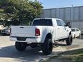 A white 2018 RAM 3500 pickup truck with a lifted suspension and large black wheels parked with its rear facing the viewer