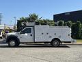 A 2011 Ford F-550 truck with a white utility body featuring multiple compartments and equipment racks on top