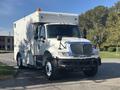 A 2008 International 4400 truck with a white body and an elevated cab featuring multiple lights and side mirrors designed for utility or service purposes