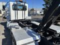A 2020 Peterbilt 330 truck featuring a metallic flatbed and hydraulic lifting mechanism designed for transporting equipment and materials