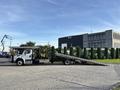 A 2022 Freightliner M2 106 flatbed tow truck with an extended ramp positioned for loading vehicles