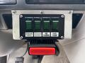A control panel with four green switches labeled for rotating lights front/rear flasher side flashers and fuel pump and a large red button below