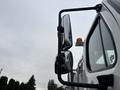 A 2013 Freightliner 114SD truck with a prominent side view mirror and an amber marker light on the roof