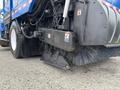 A 2013 International DuraStar 4300 street sweeper featuring a large brush attachment and a front-mounted vacuum assembly designed for cleaning roadways