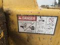 A warning label on a yellow Vermeer Corporation BC1000XL wood chipper indicating dangers such as rotating knives and thrown objects with safety instructions