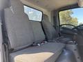Interior view of a 2022 Isuzu NQR showing two grey upholstered seats with seatbelts and a central console