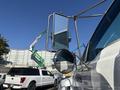 A white 2004 Ford F-750 truck with large side mirrors reflecting a nearby construction scene