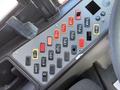 A control panel featuring a variety of switches and buttons in red, yellow, and black arranged in rows on a gray surface