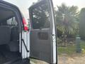 A 2021 Chevrolet Express van with the side door open revealing the interior seating and controls
