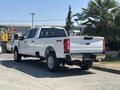 A white 2023 Ford F-350 SD truck parked with its rear facing the viewer showcasing its 4x4 and Super Duty badging