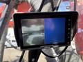 A display screen showing a split view with one side indicating a rear camera feed and the other side a blank blue screen mounted in a machine cockpit