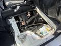 Engine compartment of a 2010 Daihatsu Hijet showing various components including hoses a reservoir and a battery location