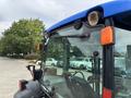 Close-up of a 2009 New Holland T4020 tractor showing the cab exterior with a blue roof and headlights mounted on the front pillars