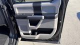 The interior door panel of a 2016 Ford F-150 featuring a combination of light gray and dark gray plastic with a handle and control buttons