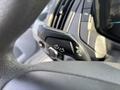 A close-up of the turn signal lever on the steering column of a 2016 Ford Transit 150 featuring directional arrows and light control buttons