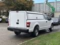 A white 2020 Ford F-150 with a rear canopy parked in a lot showing the truck's back view and wheels