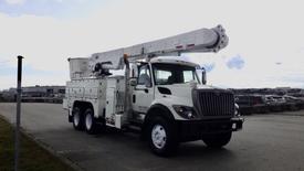A white 2008 International 7500 bucket truck with a raised aerial lift and multiple compartments on the side for tools and equipment