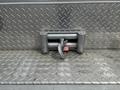 A silver winch mounted on a textured metal plate with a red securing pin