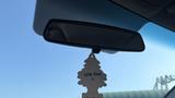 Rearview mirror of a vehicle with a hanging air freshener shaped like a tree