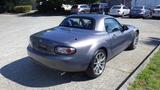 A 2007 Mazda Miata in a gray color with a sleek design and a hardtop roof features sporty alloy wheels and dual exhausts