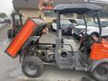 A 2010 Kubota RTV 900 utility vehicle with an orange bed raised for loading, featuring a grey cabin and large wheels