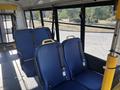Interior of a 2017 Ford Transit-350 featuring rows of blue seats with yellow handles and seatbelts arranged in a passenger transport configuration