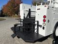 A 2005 Freightliner M2 106 truck with a utility body featuring a black platform and metal railings at the rear