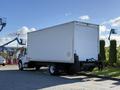 A 2012 Freightliner M2 106 box truck with a white cargo area and a black chassis parked on a roadside