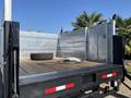 A 2019 Ford F-550 truck with a flatbed featuring a wooden floor and metal sides a spare tire rests on the bed along with some cables