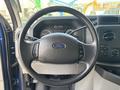 A steering wheel of a 2013 Ford E-350 Super Duty featuring the Ford logo and various control buttons on the side