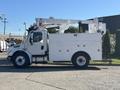White 2005 Freightliner M2 106 bucket truck with a raised aerial lift and storage compartments on the side