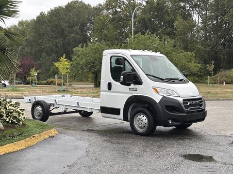 A 2023 RAM Promaster 3500 chassis cab in white with a flatbed design featuring large front headlights and a distinctive grill