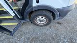 A 2021 Ford Transit with a close-up view of its front tire showing some wear and tear and partially visible wheel rim
