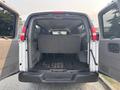 The interior of a 2021 Chevrolet Express with rear doors open revealing a spacious cargo area and a bench seat folded down
