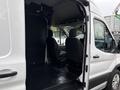 A 2020 Ford Transit 250 with an open side door showing two front seats and a spacious cargo area in the rear