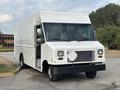 A white 2018 Ford Econoline delivery truck with a square front and large windshield is parked with the driver's side door open