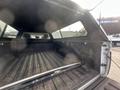 The interior of a 2012 RAM 2500 truck bed showing a black rubberized surface and a metal rail along the top edge with some dirt and wear visible