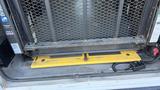 A 2021 Ford Transit with an open rear door revealing a lift platform and controls with a yellow safety mat at the base