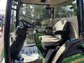 Interior view of a 2021 John Deere 1575 mower with a black steering wheel and a cushioned seat with armrests