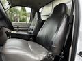 The interior of a 2009 Ford F-550 showing two gray leather seats with some wear and a black console in between