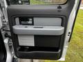 Close-up of the driver's side door panel of a 2014 Ford F-150 showing the handle armrest and storage compartment