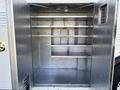 An empty cargo area with several horizontal shelves and compartments inside a 2008 International 4400 truck body