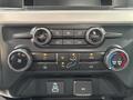 The dashboard control panel of a 2023 Ford F-450 Super Duty featuring knobs and buttons for volume tuning climate control and air conditioning