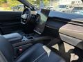 Interior of a 2023 Fisker Ocean featuring a minimalist dashboard a large central touchscreen and black leather seating