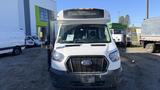 A 2021 Ford Transit van with a front view featuring a large windshield and a sign displaying "SORRY NOT IN SERVICE" on top