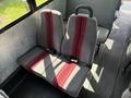 Two gray seats with red stripes and seatbelts positioned side by side inside a vehicle